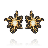 Brinco Médio Preto Ouro Peregrinar Camila Klein, com design floral orgânico e sofisticado, confeccionado em resina preta com detalhes metálicos de ramificações e acabamento em banho de ouro velho. Possui cristal central em formato de gota com tonalidade clara e acabamento facetado, criando contraste elegante entre o preto, o dourado e o brilho do cristal. A composição inspirada em elementos da natureza destaca o estilo marcante e contemporâneo da peça.