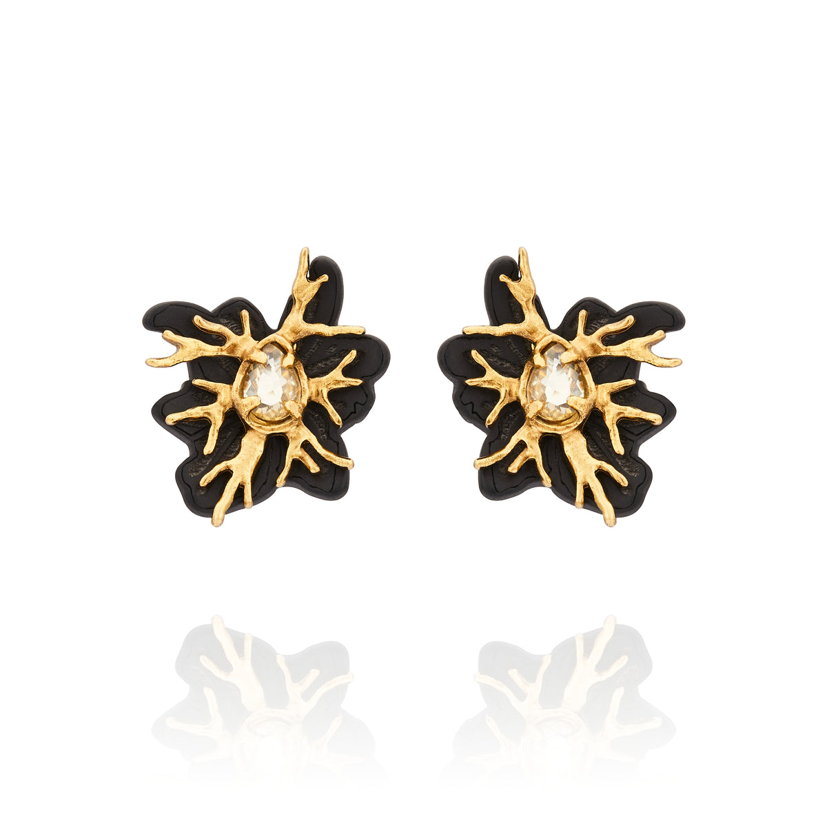 Brinco pequeno Preto Ouro Peregrinar Camila Klein, com design orgânico inspirado em galhos, resina preta e cristal central em tom champagne. Confeccionado em cristais, resina preta e metais com banho em ouro velho, combina contraste, sofisticação e personalidade em uma peça marcante e elegante.