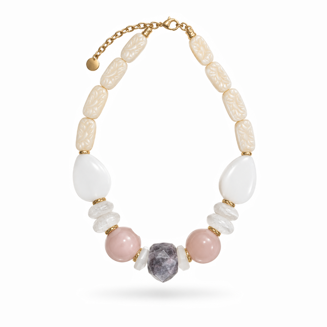 Colar Camila Klein Verão em Cores com pedras naturais em tons de bege, branco, rosé e marrom, combinadas em diferentes formatos, tamanhos e texturas. O design apresenta pedras alongadas em tom dourado, elementos orgânicos claros e contas esféricas rosadas, finalizado com uma pedra central escura de formato irregular. A corrente dourada valoriza a composição, traduzindo o encontro entre natureza, design autoral e elegância.