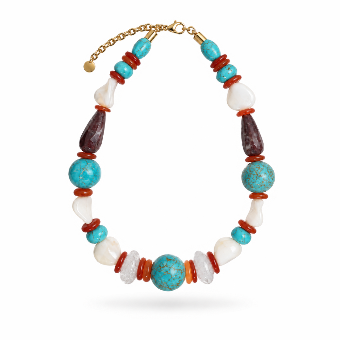 Colar Camila Klein Verão em Cores com pedras naturais em tons de turquesa, azul, marrom, vermelho, creme e verde, combinadas em diferentes formatos, tamanhos e texturas. O design reúne contas esféricas, pedras irregulares e elementos orgânicos em uma composição vibrante e sofisticada. A corrente dourada complementa a peça, destacando o design autoral e a beleza singular das pedras. Um acessório marcante para produções de verão com frescor, elegância e personalidade.