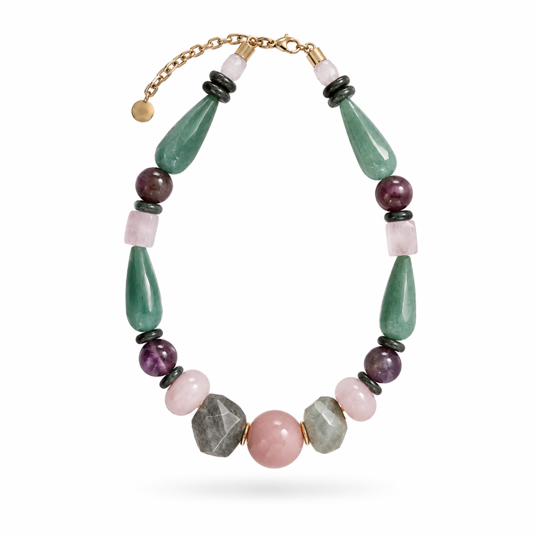 Colar Camila Klein Verão em Cores com pedras naturais em tons de verde, vinho, bege, cinza e marrom, combinadas em diferentes formatos, tamanhos e texturas. O design apresenta pedras alongadas e contas esféricas, incluindo uma pedra central em tom rosado, criando uma composição orgânica, sofisticada e autêntica. A corrente dourada complementa a peça, valorizando o design autoral e a beleza singular da natureza.