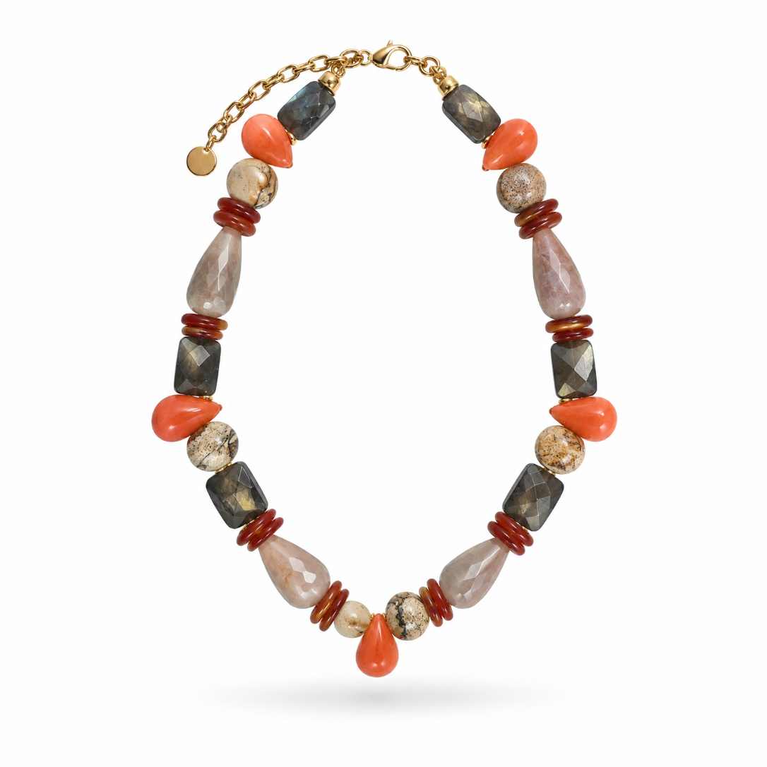 Colar Camila Klein Verão em Cores com pedras naturais em tons de laranja, marrom, preto, verde e bege, combinadas em diferentes formatos, tamanhos e texturas. O design reúne contas esféricas, pedras alongadas e elementos orgânicos em uma composição vibrante e sofisticada. Detalhes dourados complementam a peça, valorizando o design autoral e a beleza singular das pedras naturais. Um acessório marcante para produções de verão com frescor, elegância e personalidade.