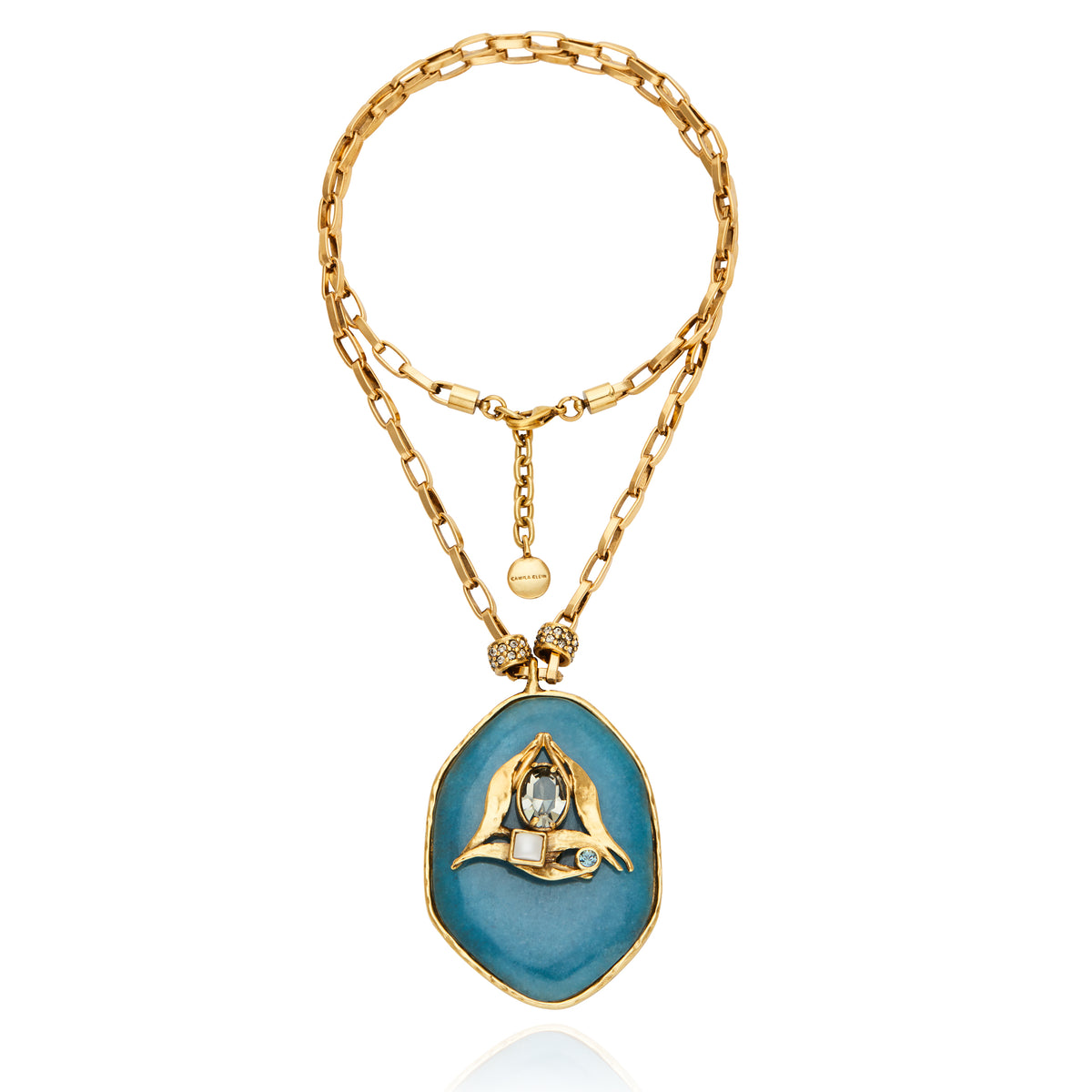 Colar Camila Klein com corrente dourada e pingente oval em pedra natural azul, com detalhe central em metal dourado. A peça combina cores e texturas orgânicas em um design autoral, sofisticado e vibrante, inspirado na leveza do verão. Ideal para compor produções elegantes e cheias de personalidade, valorizando a beleza singular das pedras naturais.