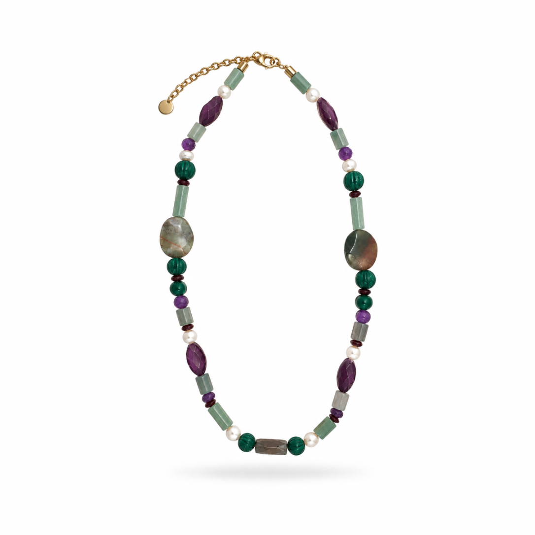 Colar Camila Klein Verão em Cores com pedras naturais em tons de verde, roxo, azul, vinho, cinza e marrom, combinadas em diferentes formatos, tamanhos e texturas. O design alongado reúne contas esféricas, pedras irregulares e elementos delicados em uma composição colorida e sofisticada. Detalhes dourados complementam a peça, valorizando o design autoral e a beleza singular das pedras naturais. Um acessório marcante para produções de verão com frescor, elegância e personalidade.