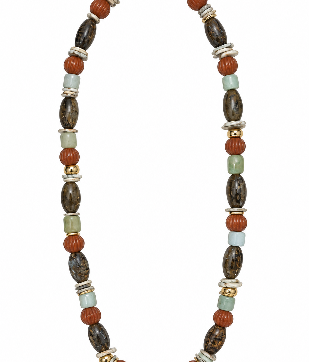 Colar Camila Klein Verão em Cores com pedras naturais em tons terrosos, verdes, marrons e escuros, combinadas em diferentes formatos e texturas. O design alongado reúne contas esféricas, pedras irregulares e elementos dourados em uma composição sofisticada e autêntica. Uma criação autoral que celebra as cores e a beleza singular da natureza, ideal para produções de verão com elegância, frescor e personalidade.