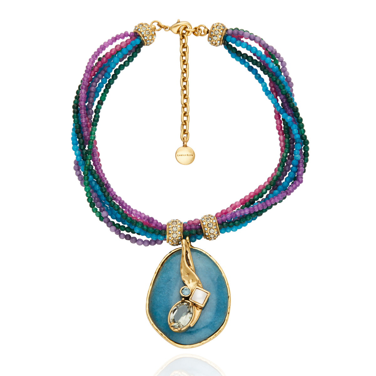 Colar Camila Klein inspirado no verão, com cordão trançado em tons de azul e roxo, detalhes dourados e pingente circular em pedra natural escura. O design autoral combina cores, texturas e formas orgânicas em uma peça sofisticada e vibrante, perfeita para composições leves e cheias de personalidade.