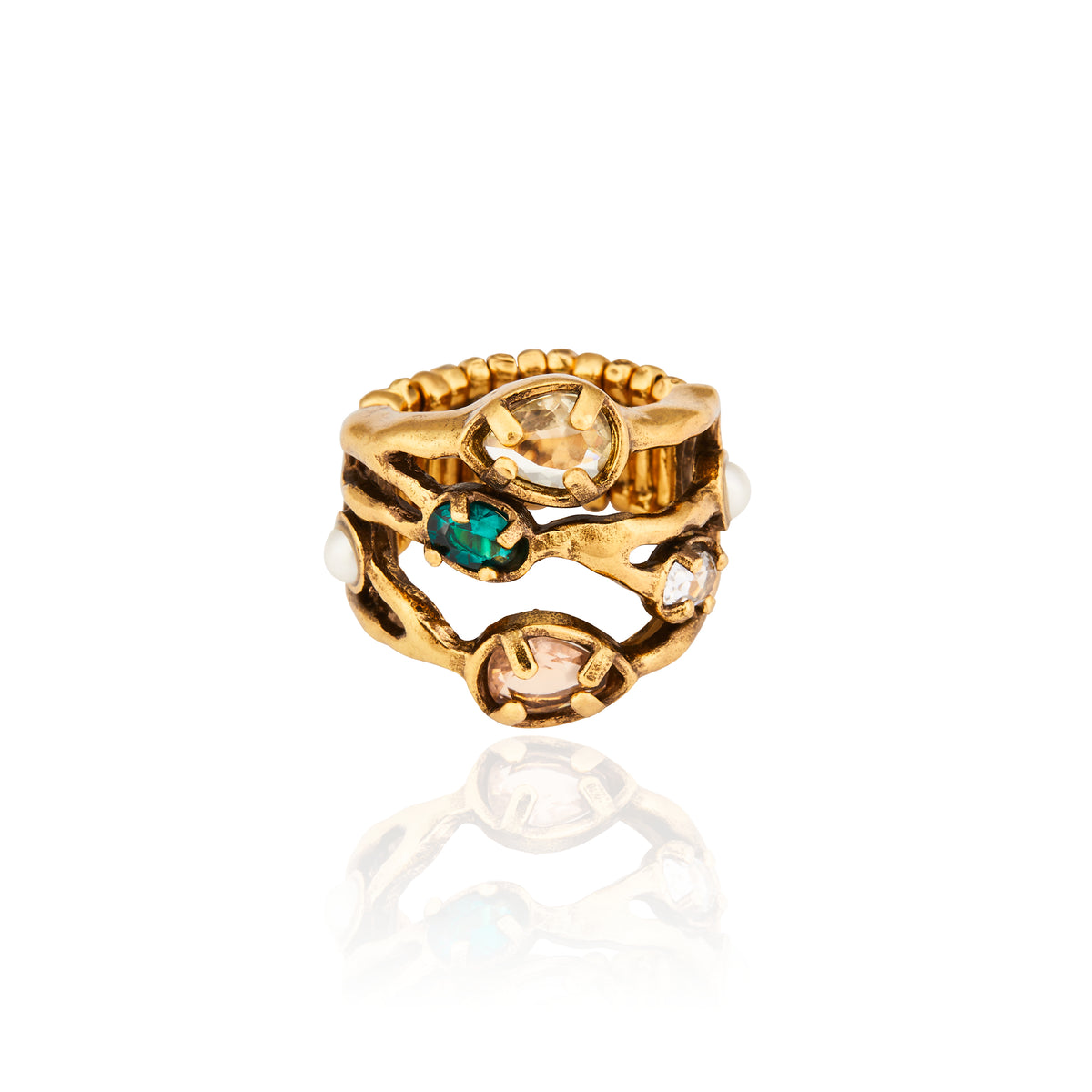 Meio Anel Cristais Ouro Peregrinar da Camila Klein, em metal com banho de ouro velho, com design orgânico e vazado formado por linhas irregulares. O anel apresenta cristais em diferentes tonalidades, incluindo cristal transparente, verde-azulado e rosado, aplicados em diferentes pontos da peça. O aro possui acabamento texturizado e detalhes que remetem a formas naturais, com uma composição sofisticada e artesanal. Fotografia do anel sobre fundo branco, com reflexo da peça na superfície.