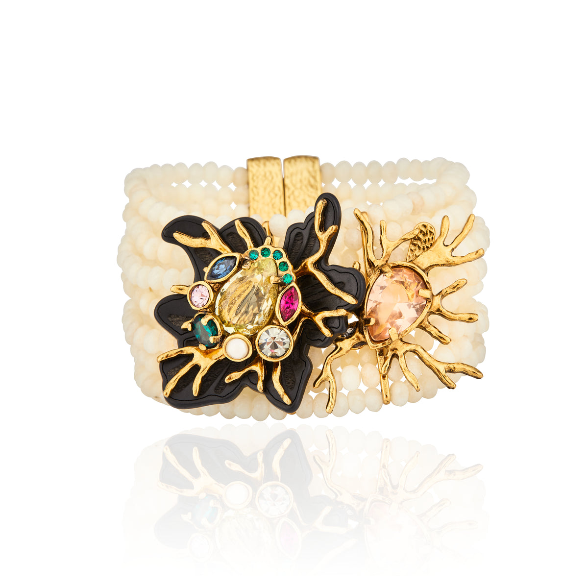 Pulseira larga Camila Klein modelo Peregrinar com fios de contas em jade creme, detalhe central assimétrico em resina preta e metal ouro velho com cristais lapidados coloridos, exibida sobre fundo branco com reflexo.